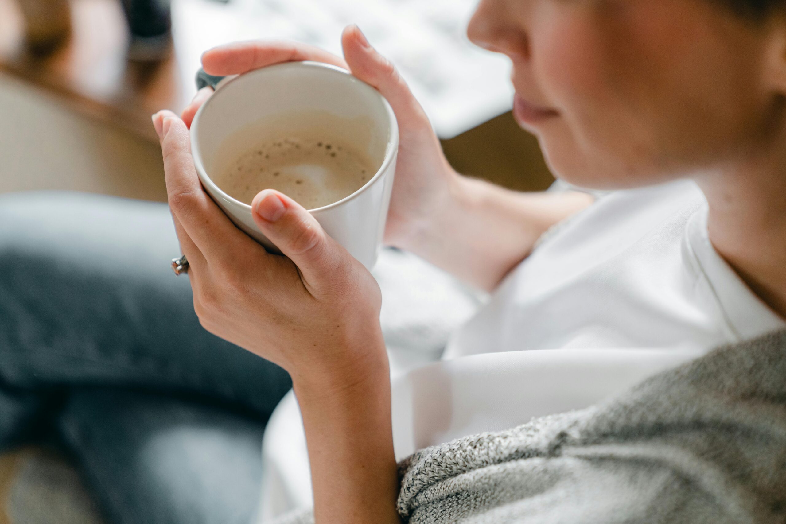 A woman enjoys a warm cup of coffee indoors, capturing a moment of relaxation.